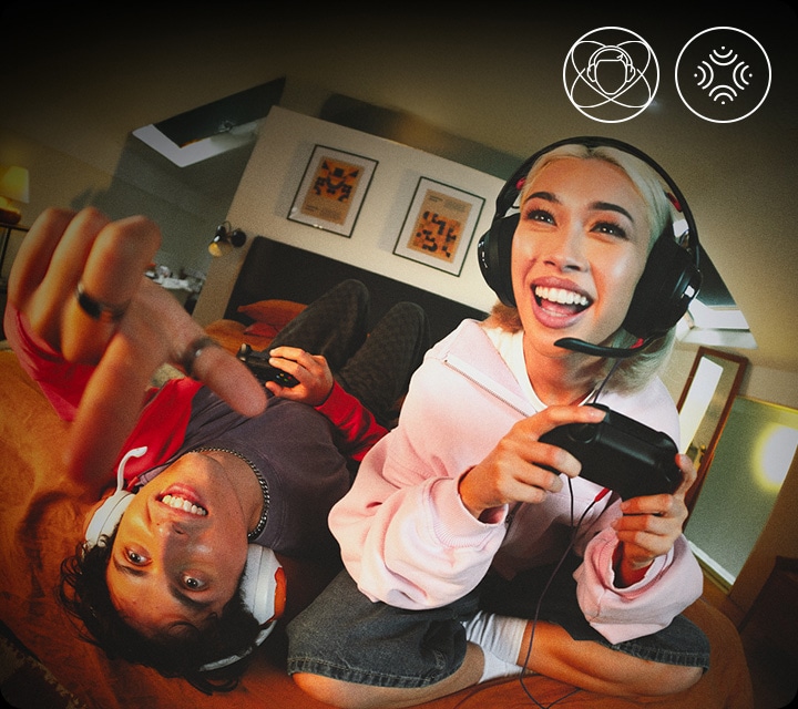 블랙 색상의 헤드폰을 착용한 여성은 침대에 앉아서 게임을 하고 있으며, 화이트 색상의 헤드폰을 착용한 남성은 침대에 누워서 게임을 하고 있습니다.