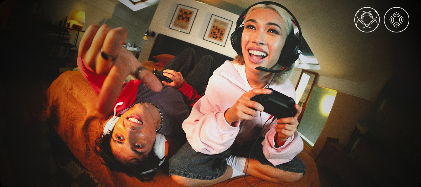 블랙 색상의 헤드폰을 착용한 여성은 침대에 앉아서 게임을 하고 있으며, 화이트 색상의 헤드폰을 착용한 남성은 침대에 누워서 게임을 하고 있습니다.