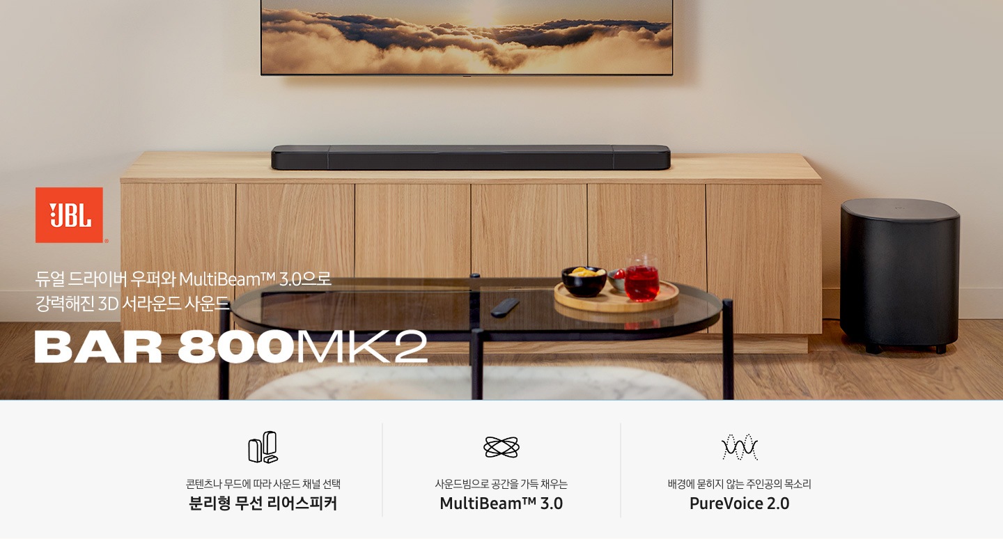 장식장 위에 사운드바가 놓여 있으며, 장식장 오른쪽 아래에는 서브우퍼가 놓여 있습니다. 장식장 앞에는 다과가 올라간 트레이가 놓인 테이블이 있습니다. 왼쪽 하단에는 JBL 로고와 ‘듀얼 드라이버 우퍼와 MultiBeam™ 3.0으로 강력해진 3D 서라운드 사운드’ 문구, 사운드바 모델명인 ‘BAR 800 MK2’가 기재되어 있습니다. 이미지 하단에는 ‘콘텐츠나 무드에 따라 사운드 채널 선택 분리형 무선 리어스피커‘, ‘사운드빔으로 공간을 가득 채우는 MultiBeam™ 3.0’, ‘배경에 묻히지 않는 주인공의 목소리 PureVoice 2.0‘ 문구와 아이콘이 있습니다.