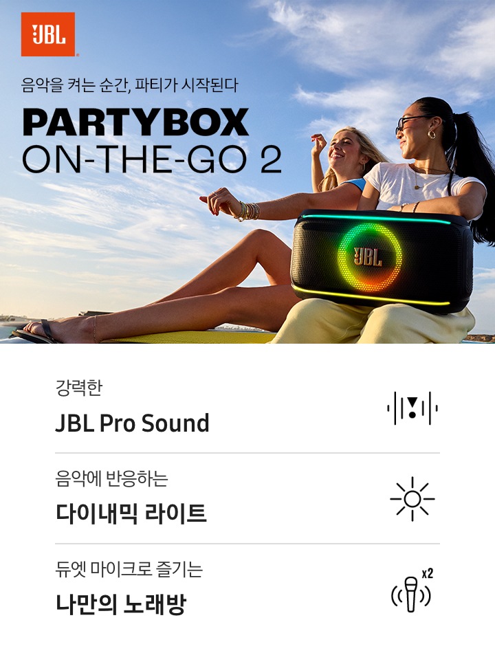여성 두명이 앉아 있습니다. 흰색 티를 입은 여성이 스피커를 무릎에 올려 두었습니다. 왼쪽에는 JBL 로고와 ‘음악을 켜는 순간, 파티가 시작된다‘ 문구와 모델명인 ‘PARTYBOX ON-THE-GO 2’가 기재되어 있습니다. 이미지 하단에는 ‘강력한 JBL Pro Sound’, ‘음악에 반응하는 다이내믹 라이트‘, ‘듀엣 마이크로 즐기는 나만의 노래방‘ 문구와 아이콘이 있습니다.