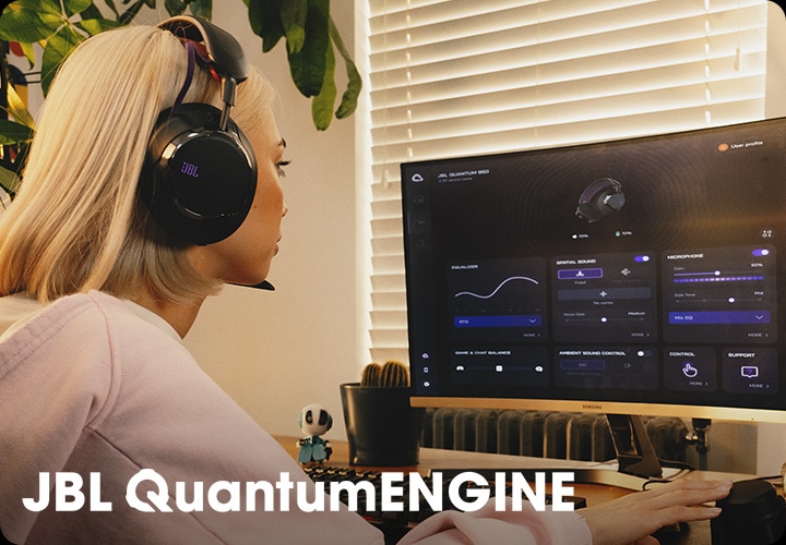 헤드폰을 착용한 여성이 컴퓨터로 JBL QuantumENGINE 대시보드를 보고 있습니다.