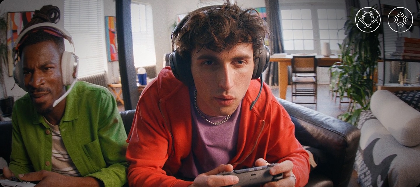 화이트 색상의 헤드폰을 착용한 남성과 블랙 색상의 헤드폰을 착용한 남성이 게임을 하고 있습니다.