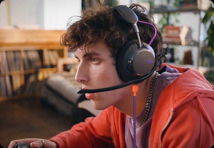 케이블이 연결된 헤드폰을 착용한 남성이 게임을 하고 있습니다.