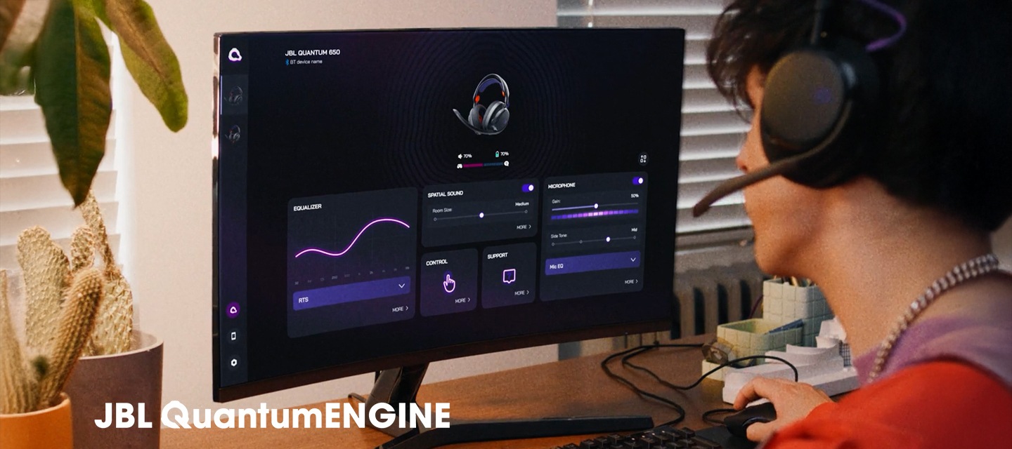 헤드폰을 착용한 남성이 컴퓨터로 JBL QuantumENGINE 대시보드를 보고 있습니다.