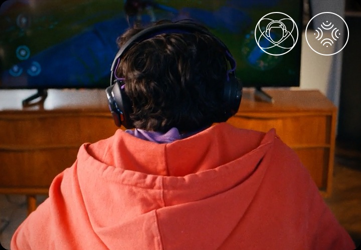 헤드폰을 착용한 남성이 소파에 앉아서 TV로 게임을 하고 있습니다.