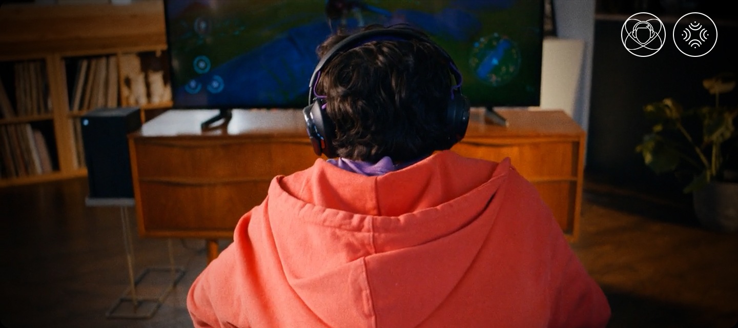 헤드폰을 착용한 남성이 소파에 앉아서 TV로 게임을 하고 있습니다.