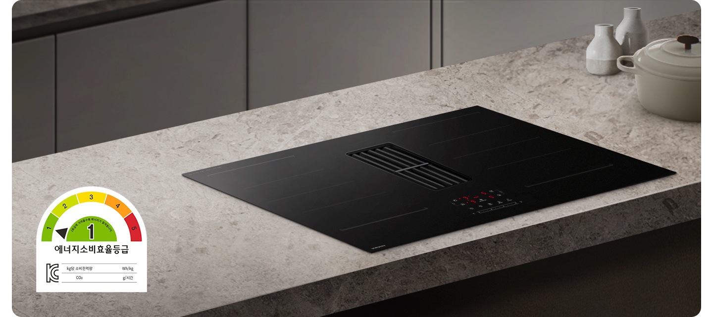 어두운 베이지 톤의 주방을 배경으로 이미지 왼쪽 하단 부분에는 에너지 소비효율 1등급 로고가 노출되어 있고 이미지 중간 부분에는 어두운 베이지 색상의 상판과 설치된 Infinite Line 후드일체형 인덕션이 있습니다. 인덕션 오른쪽 부분에는 아이보리 색상의 냄비와 화병 2개가 겹쳐 놓여 있습니다.