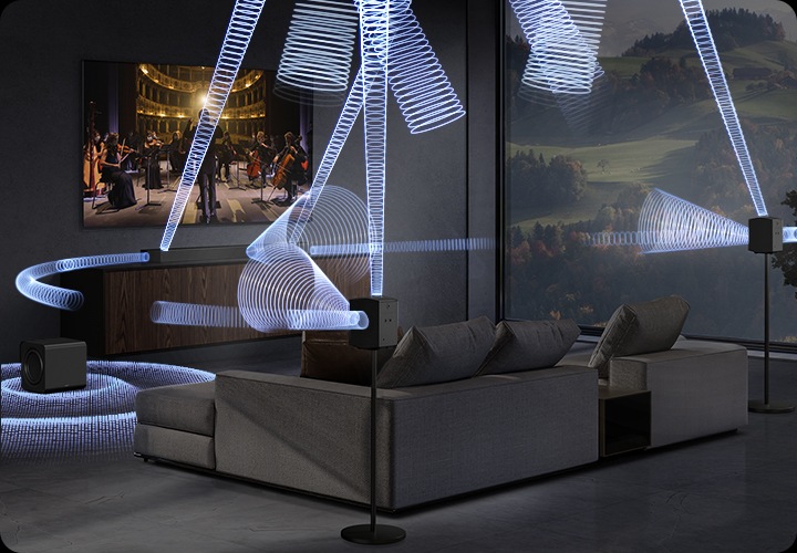 거실 벽에 TV기 설치되어 있으며, 그 아래에는 사운드바 본체가 올라가있는 장식장이 있습니다. 장식장에 왼쪽에는 서브 우퍼가 놓여 있습니다. TV 앞에는 소파와 테이블이 놓여 있으며, 소파 뒤 스탠드에는 리어 스피커가 설치되어 있습니다. TV 화면에는 첼로와 바이올린을 연주하는 사람들이 보이며, TV 하단에 있는 사운드바에서 음향효과가 나오고 있습니다.