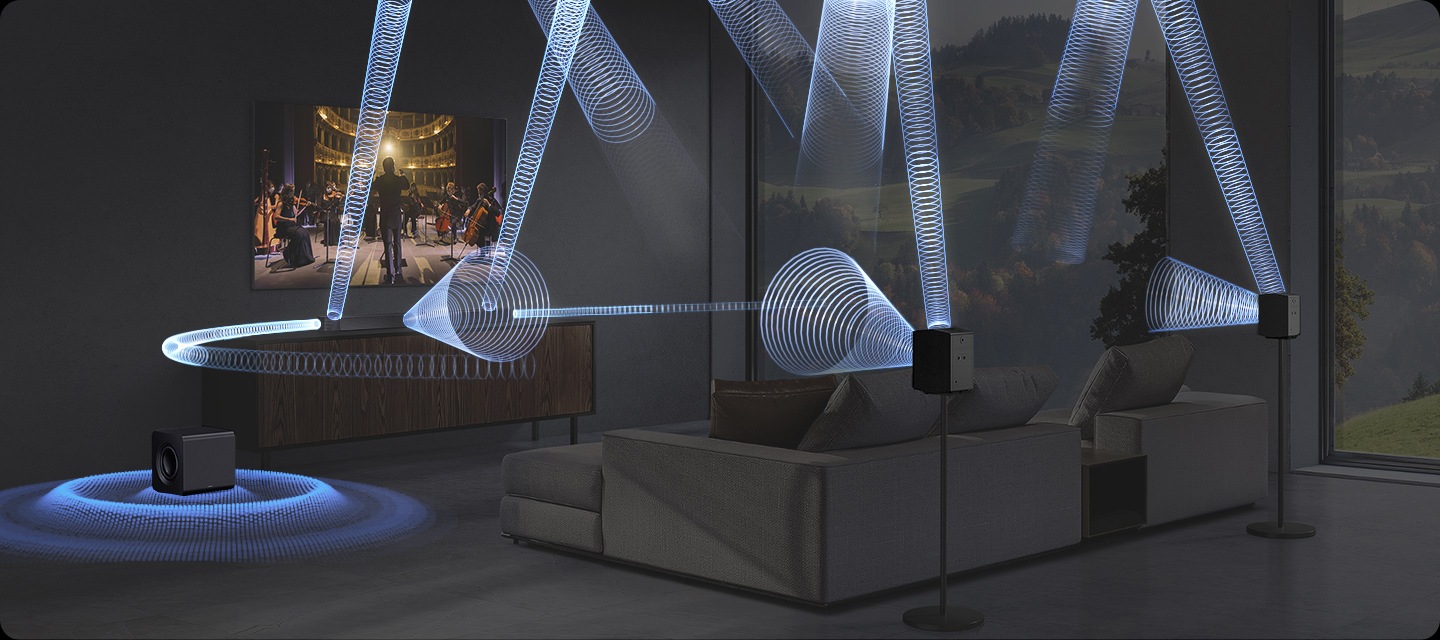 거실 벽에 TV기 설치되어 있으며, 그 아래에는 사운드바 본체가 올라가있는 장식장이 있습니다. 장식장에 왼쪽에는 서브 우퍼가 놓여 있습니다. TV 앞에는 소파와 테이블이 놓여 있으며, 소파 뒤 스탠드에는 리어 스피커가 설치되어 있습니다. TV 화면에는 첼로와 바이올린을 연주하는 사람들이 보이며, TV 하단에 있는 사운드바에서 음향효과가 나오고 있습니다.