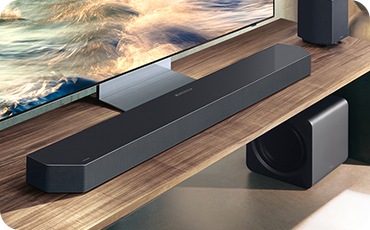 테이블 위에 TV와 사운드바, 리어 스피커가 놓여 있으며, 테이블 아래에는 서브우퍼가 놓여 있습니다.