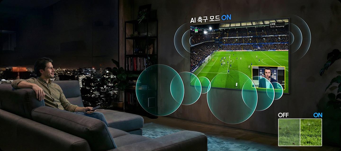 남성이 소파에 앉아서 벽에 설치된 TV를 보고 있습니다. TV 화면에는 축구 경기가 보여지고 있습니다.