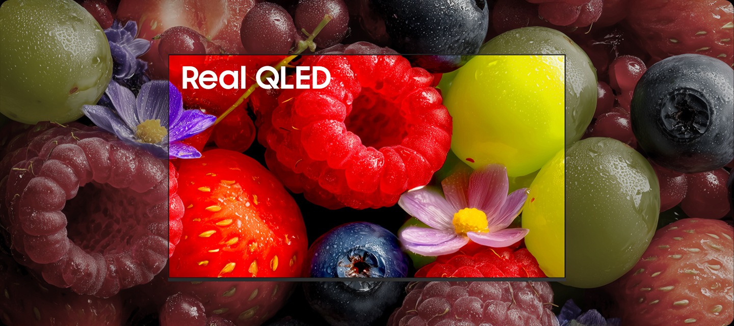 TV화면에 과일들이 보여지고 있으며, TV 중간에 ‘Real QLED’라고 표시된 부분의 과일의 색상이 선명합니다.