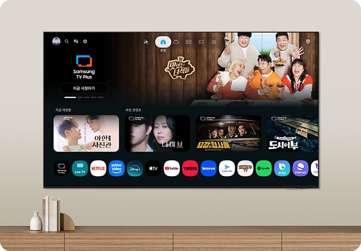 벽에 TV가 설치되어 있으며, 화면 속에는 여러 예능과 드라만 메인 화면이 보입니다.