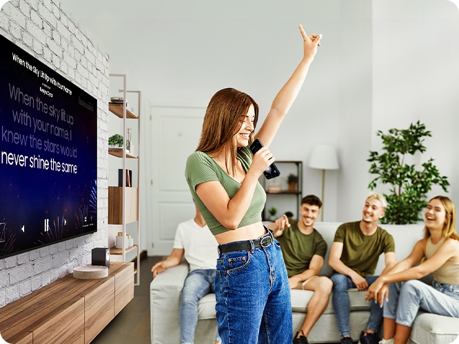 여성이 TV 노래방 기능을 활용하여 노래를 부르고 있습니다.