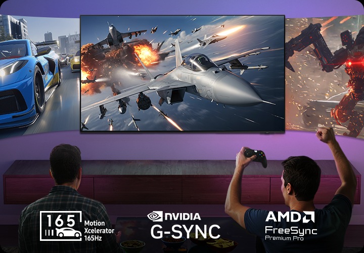 남성 두 명이 소파에 앉아서 게임을 하고 있습니다. 벽에는 TV가 설치되어 있으며 화면에는 자동차 게임, 우주선 게임, 로봇 게임이 보입니다.