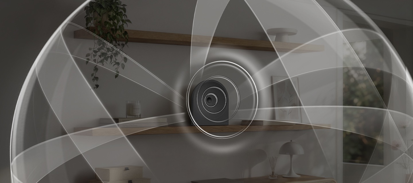 선반 위에 음향효과가 퍼져 나오는 스피커가 놓여 있습니다. 스피커 왼쪽에는 책들과 향초가 놓여 있으며, 오른쪽에는 책과 액자가 놓여 있습니다. 스피커 위쪽 선반에는 화분이 아래쪽 선반에는 조명, 방향제, 책, 서랍 등이 놓여 있습니다. 