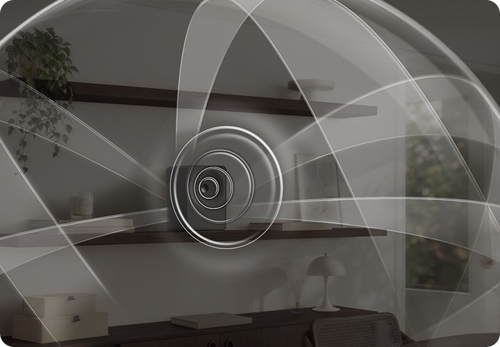 선반 위에 음향효과가 퍼져 나오는 스피커가 놓여 있습니다. 스피커 왼쪽에는 책들과 향초가 놓여 있으며, 오른쪽에는 책과 액자가 놓여 있습니다. 스피커 위쪽 선반에는 화분이 아래쪽 선반에는 조명, 방향제, 책, 서랍 등이 놓여 있습니다. 