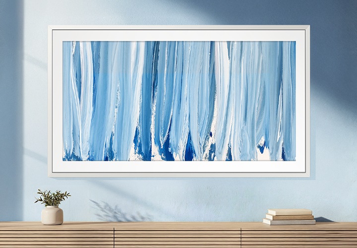 푸른색 벽에 TV가 설치되어 있습니다. TV 아래에는 화분과 책이 놓인 장식장이 있습니다.