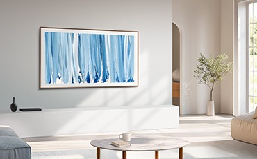 거실 벽에 TV가 설치되어 있습니다. TV 아래에는 화병이 놓인 장식장이 있습니다. 장식장 앞에는 테이블과 소파가 놓여 있습니다.