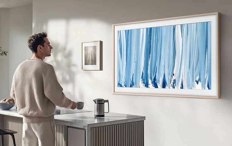 남성이 주방 벽에 설치된 TV를 보고 있습니다