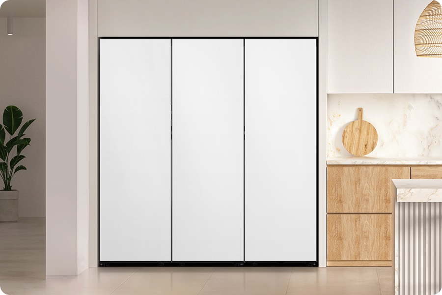 2인 가구. 밝은 그레이톤 냉장고장에 냉장고, 냉동고, 김치플러스 1도어가 페어로 설치되어 있습니다. 냉장고장 우측에는 화이트톤 상부장과 우드톤 하부장이 나와있고 위에 도마가 올려져 있습니다. 하부장 앞쪽으로는 식탁이 있는 연출된 이미지 입니다.