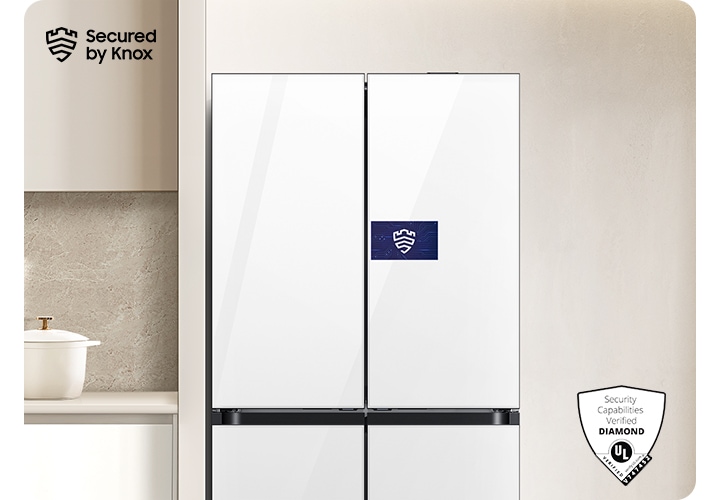 베이지톤 벽면에 패밀리허브  냉장고가 설치되어 있고 스크린 부분에 Knox 보안 로고가 나와있는 연출된 이미지 입니다. 냉장고 좌측에는 화이트톤 하부장 위 냄비, 도마 등 오브제가 놓여있고 우측에는 통창이 약간 나와있는 연출된 이미지입니다.