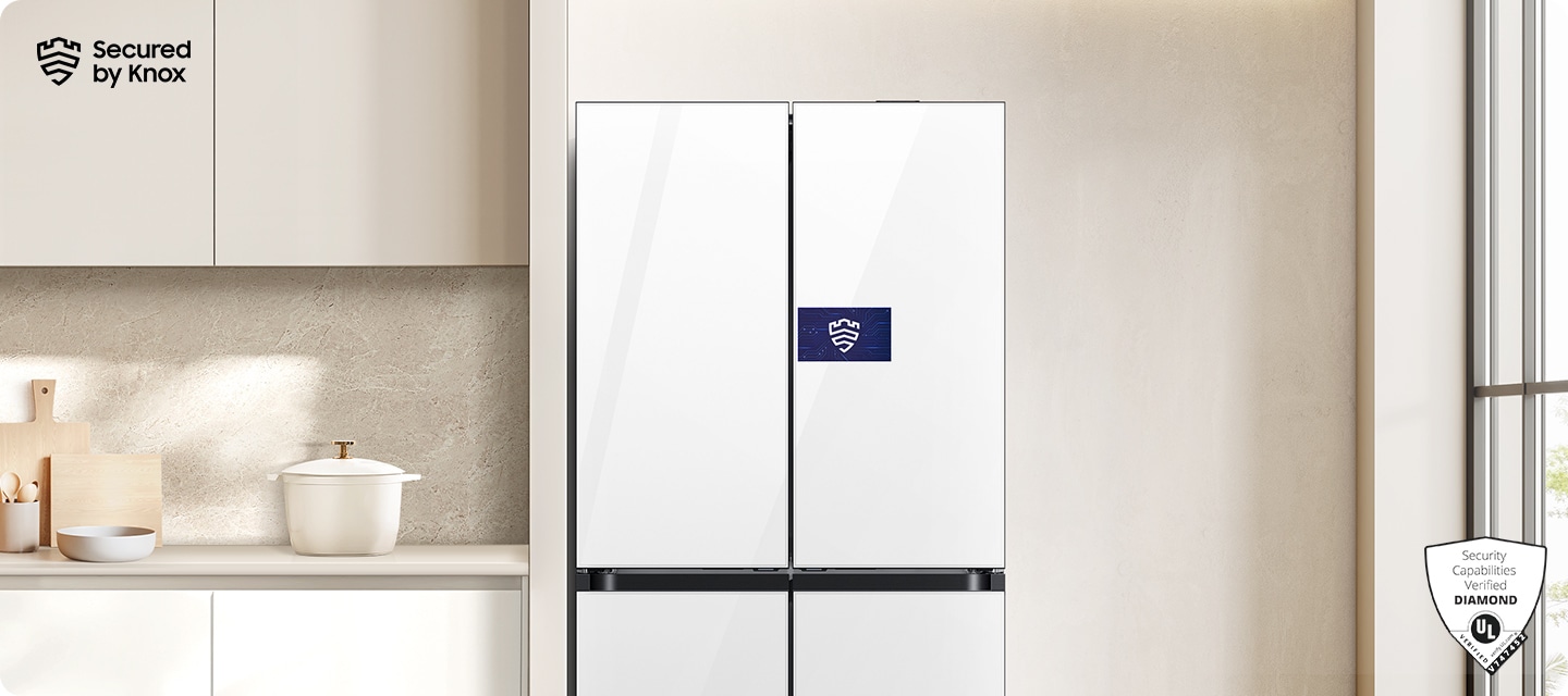 베이지톤 벽면에 패밀리허브  냉장고가 설치되어 있고 스크린 부분에 Knox 보안 로고가 나와있는 연출된 이미지 입니다. 냉장고 좌측에는 화이트톤 하부장 위 냄비, 도마 등 오브제가 놓여있고 우측에는 통창이 약간 나와있는 연출된 이미지입니다.