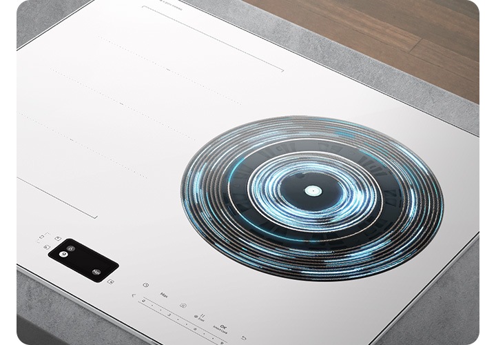 오른쪽 상단에는 진한 갈색의 마룻바닥이 있고 그 아래 회색 상판이 깔린 주방 테이블 위로 인덕션이 설치되어 있는 모습이 확대되어 있습니다. 인덕션의 오른쪽 화구의 가열 영역이 파란색 선들과 원형으로 표현되어 있습니다.