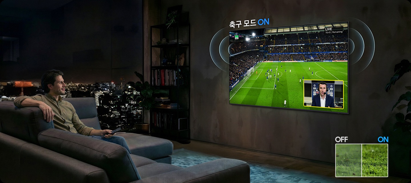 남성이 소파에 앉아서 벽에 설치된 TV를 보고 있습니다. TV 화면에는 축구 경기가 보여지고 있습니다.