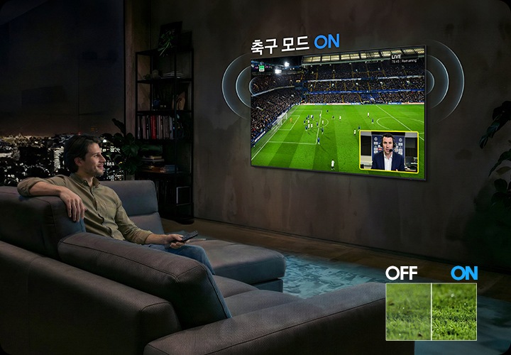 남성이 소파에 앉아서 벽에 설치된 TV를 보고 있습니다. TV 화면에는 축구 경기가 보여지고 있습니다.