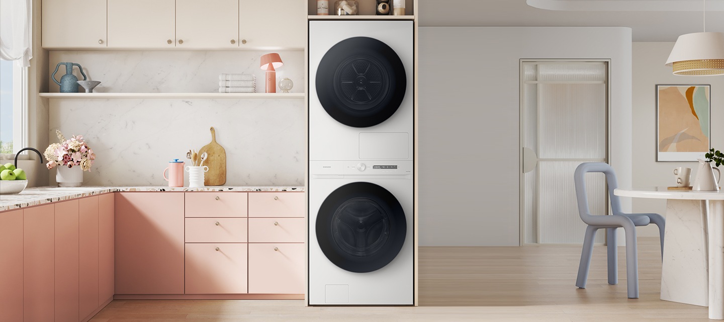 전체적으로 핑크색으로 주방에 화이트 색 원바디 제품이 있습니다. 제품 죄측에는 주방 서랍장 있고,  우측에는 식탐과 의자가 있습니다. 의자 뒤에는 다용도실 문이 보이고 옆에는 벽걸이 그림이 있습니다.