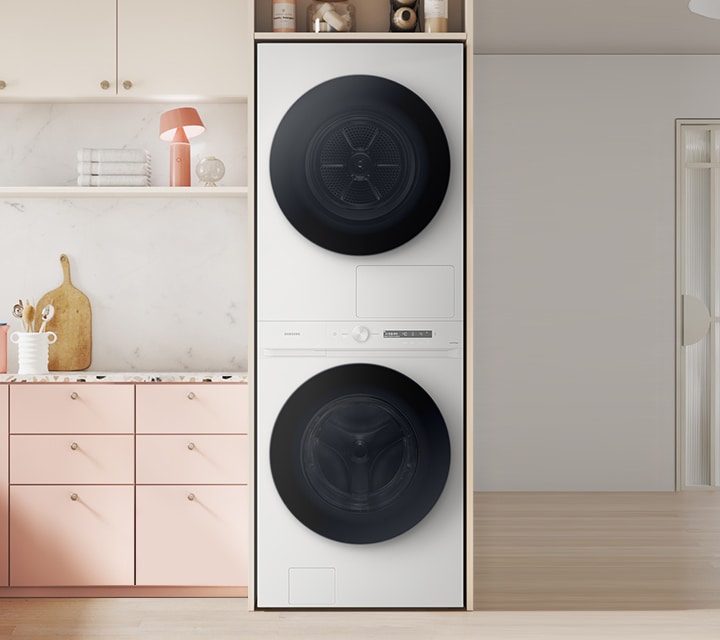 전체적으로 핑크색으로 주방에 화이트 색 원바디 제품이 있습니다. 제품 죄측에는 주방 서랍장 있고,  우측에는 식탐과 의자가 있습니다. 의자 뒤에는 다용도실 문이 보이고 옆에는 벽걸이 그림이 있습니다.