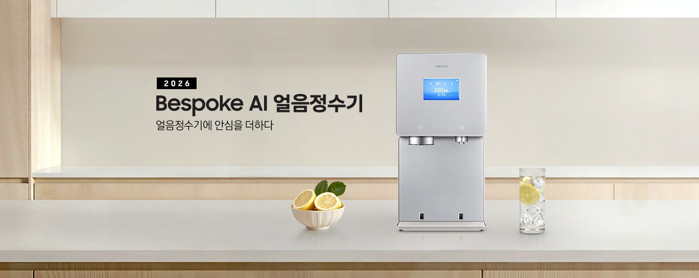 2026 Bespoke AI 얼음정수기. 얼음정수기에 안심을 더하다. 하얀색 대리석 테이블 위에 얼음정수기 사틴 베이지 컬러가 정면을 보고 설치되어 있습니다. 좌측에는 레몬이 가득 담긴 그릇이 있고 우측에는 얼음이 가득 담긴 물컵에 레몬슬라이스가 들어있습니다.