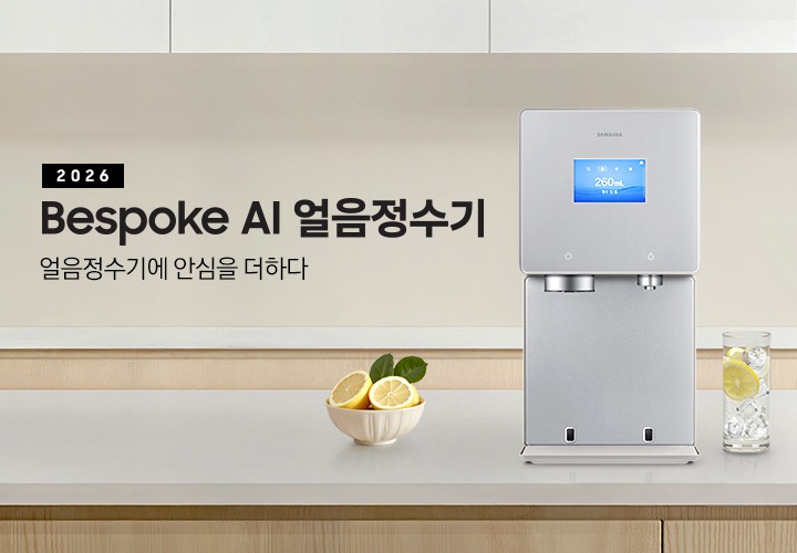 2026 Bespoke AI 얼음정수기. 얼음정수기에 안심을 더하다. 하얀색 대리석 테이블 위에 얼음정수기 사틴 베이지 컬러가 정면을 보고 설치되어 있습니다. 좌측에는 레몬이 가득 담긴 그릇이 있고 우측에는 얼음이 가득 담긴 물컵에 레몬슬라이스가 들어있습니다.