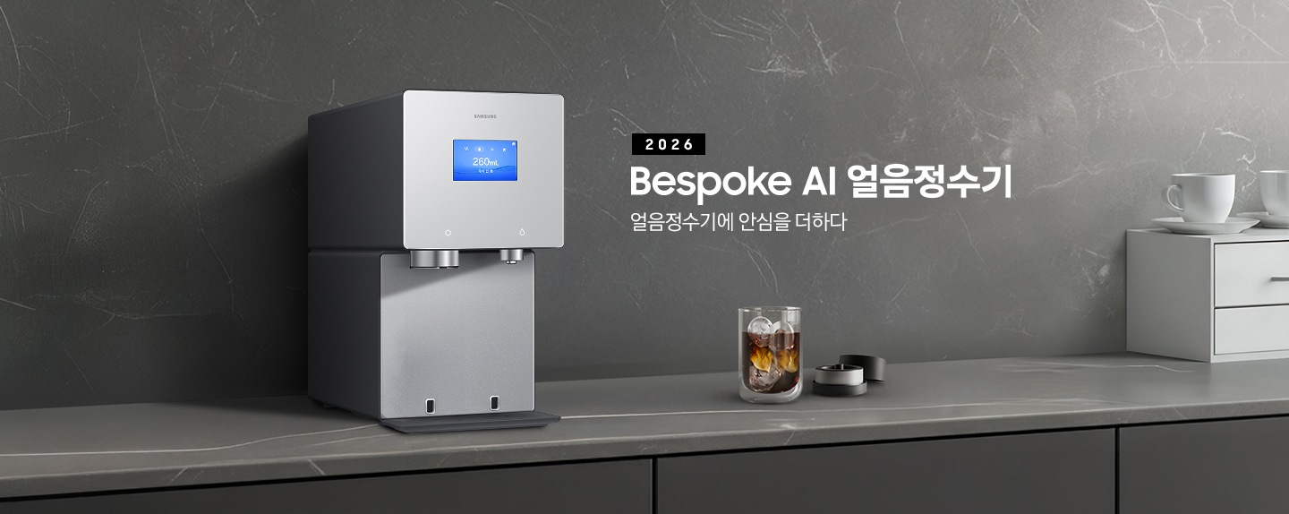 2026 Bespoke AI 얼음정수기. 얼음정수기에 안심을 더하다. 진회색 대리석 테이블 위에 얼음정수기 솝스톤 차콜 컬러가 설치되어 있는 측면 이미지 입니다. 정수기 우측에는 얼음이 가득 담긴 컵에 커피가 들어있고 옆에는 브루어 키트 뚜껑이 열려있는 이미지입니다.