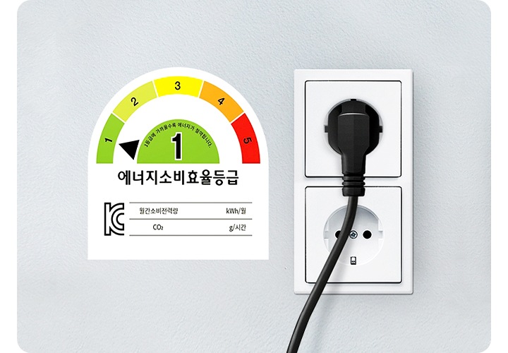 에너지 소비효율 1등급 마크와 그 옆에는 2구 콘센트가 벽에 매립 되어 있는 이미지 입니다. 위쪽 콘센트에는 어댑터가 꽂혀있습니다.