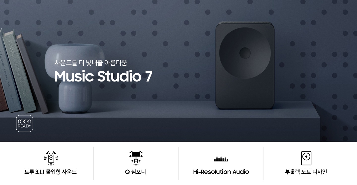 장식장 위에 스피커가 놓여 있습니다. 스피커 왼쪽에는 책들과 스탠드 조명이 놓여 있습니다. 스탠드 조명 앞으로는 ‘사운드를 더 빛내줄 아름다움‘ 문구와 스피커의 모델명인 ‘Music Studio 7’이 기재되어 있습니다. 이미지 하단에는 ‘트루 3.1.1 몰입형 사운드’, ‘Q 심포니’, ‘Hi-Resolution Audio’, ‘부훌렉 도트 디자인‘ 문구와 아이콘이 있습니다.