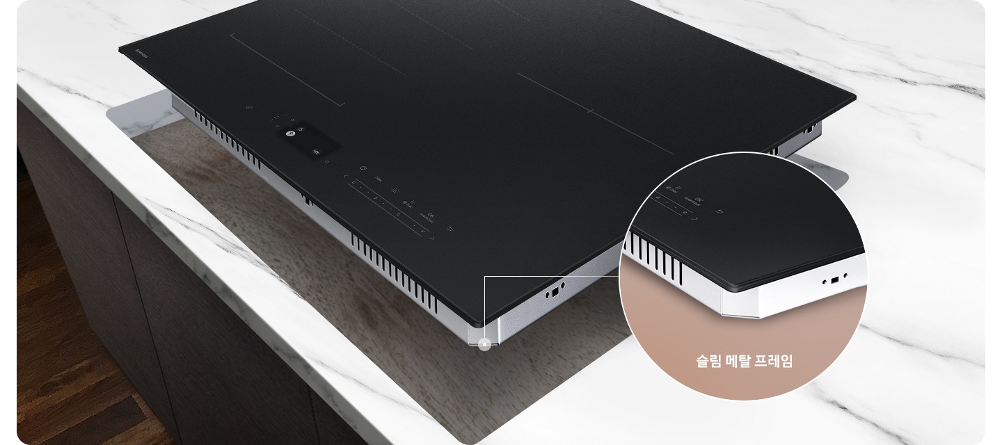 진한 갈색의 마루가 깔린 바닥이 보이고 어두운 갈색 패널의 주방 위 흰색 대리석 상판이 깔린 주방 테이블이 있습니다. 그 위에 인덕션을 설치할 부위가 타공되어 있고, 타공 된 위치 조금 위로 인덕션이 놓여 있습니다. 인덕션 오른쪽 아래에는 닷 모양의 표시와 함께 원형으로 프레임 부분이 확대되어 있습니다. 확대된 프레임 하단에는 슬림 메탈 프레임이라는 문구가 적혀 있습니다.