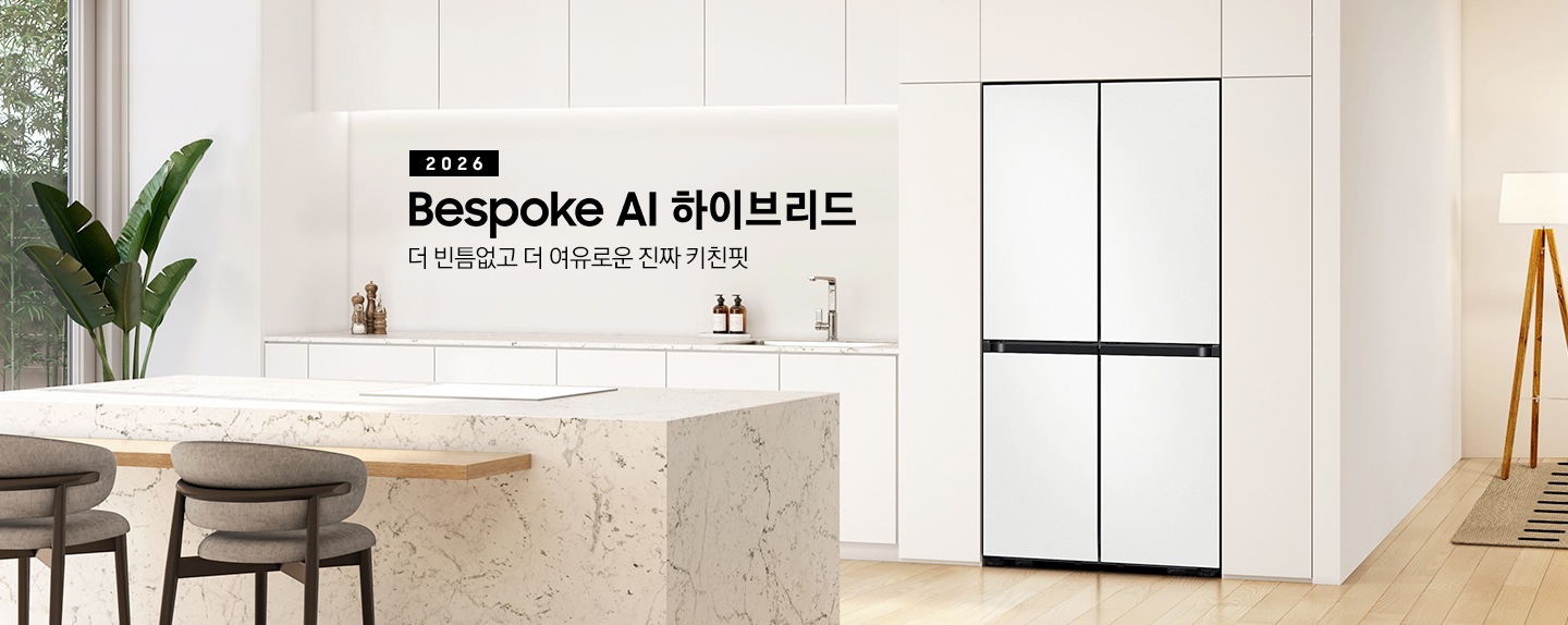 2026 Bespoke AI 하이브리드. 더 빈틈없고 더 여유로운 진짜 키친핏. 화이트톤 냉장고장에 코타 화이트 냉장고가 설치되어 있습니다. 냉장고 좌측으로 동일한 톤의 하부장이 보이고 위에 각종 오브제가 놓여있습니다. 앞쪽으로는 대리석 아일랜드 식탁과 의자가 있습니다.