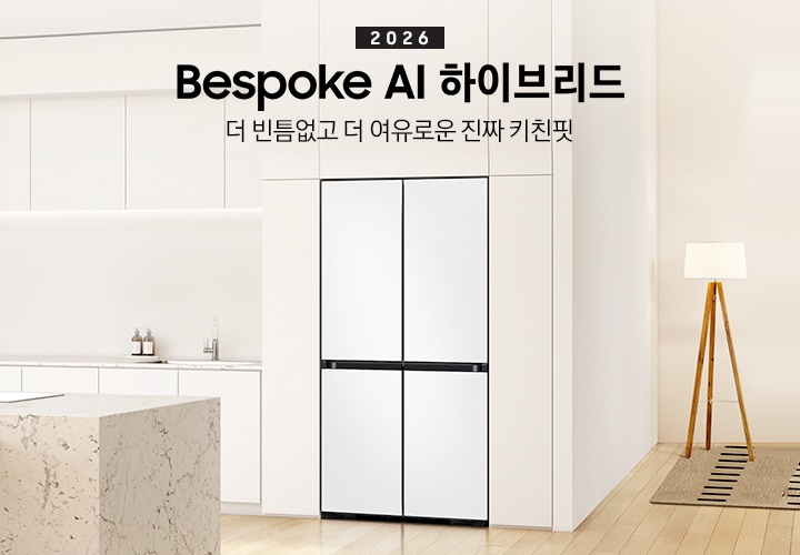 2026 Bespoke AI 하이브리드. 더 빈틈없고 더 여유로운 진짜 키친핏. 화이트톤 냉장고장에 코타 화이트 냉장고가 설치되어 있습니다. 냉장고 좌측으로 동일한 톤의 하부장이 보이고 위에 각종 오브제가 놓여있습니다. 앞쪽으로는 대리석 아일랜드 식탁과 의자가 있습니다.