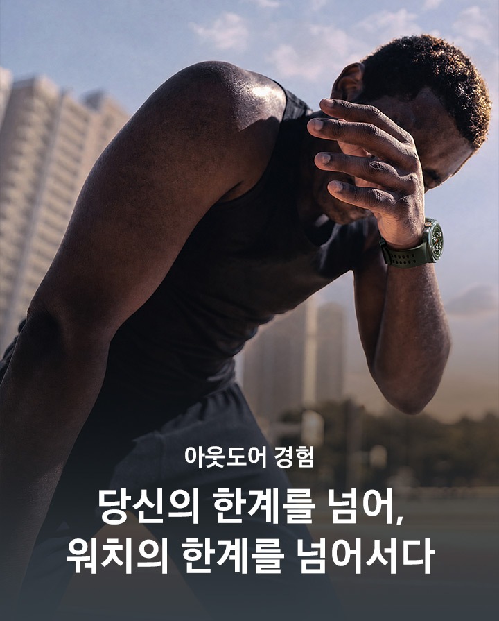 스웨트셔츠를 입고 밝은 대낮에 땀을 흘리는 남성의 모습입니다. 손목에는 올리브 색상의 마린 밴드를 장착한 티타늄 실버 색상의 갤럭시 워치 울트라2를 착용하고 있으며 운동 후에 손으로 얼굴의 땀을 닦고 있습니다.