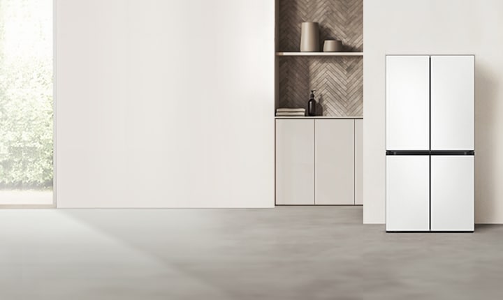베이지톤 주방에 정면으로 배치된 BESPOKE 냉장고, 창문과 주방 선반이 냉장고 좌측에 있으며, 조명 아래 테이블과 의자가 냉장고 우측에 있다.