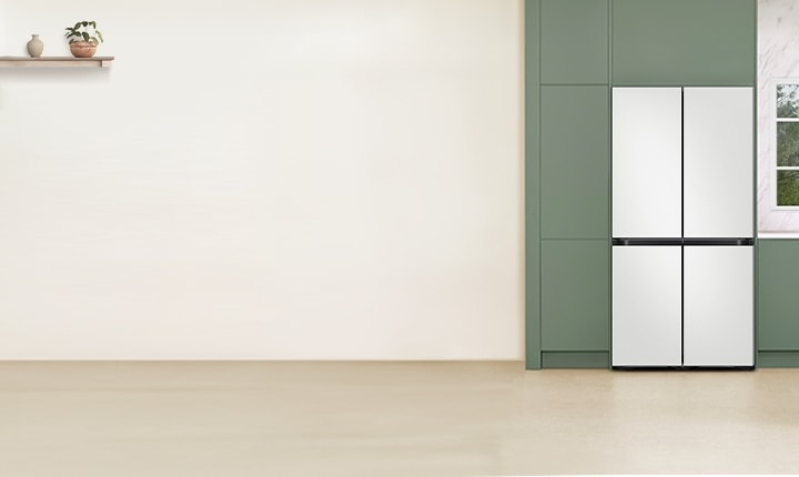 베이지톤 주방에 정면으로 배치된 BESPOKE 냉장고, 창문과 주방 선반이 냉장고 좌측에 있으며, 조명 아래 테이블과 의자가 냉장고 우측에 있다.