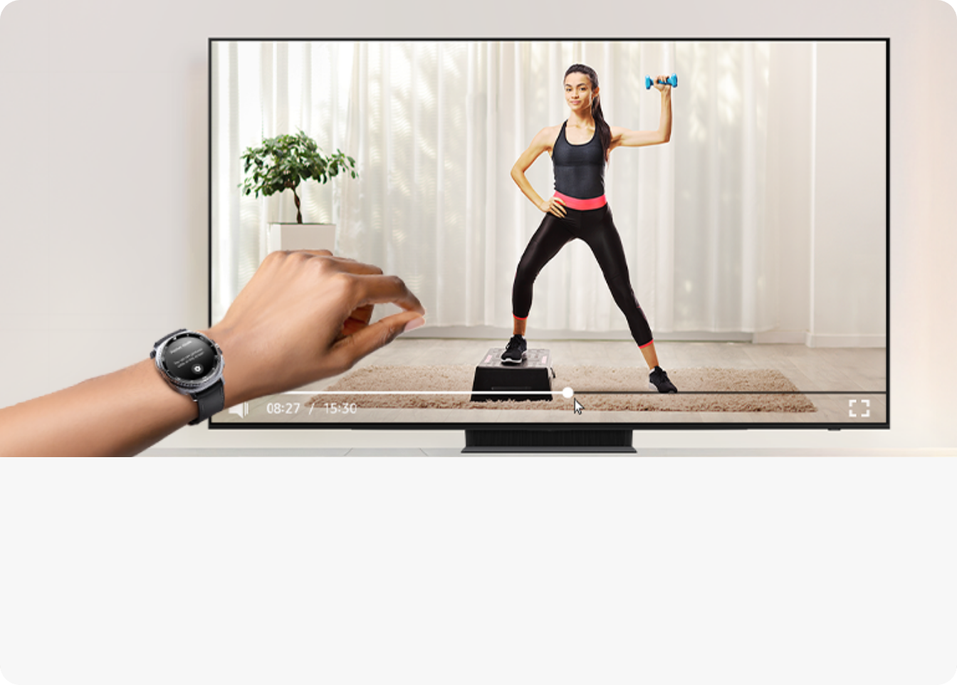 왼편에 갤럭시 워치를 착용한 손목이 보이며 중앙 뒷편의 TV 화면에는 홈트레이닝 영상이 나오고 있다
