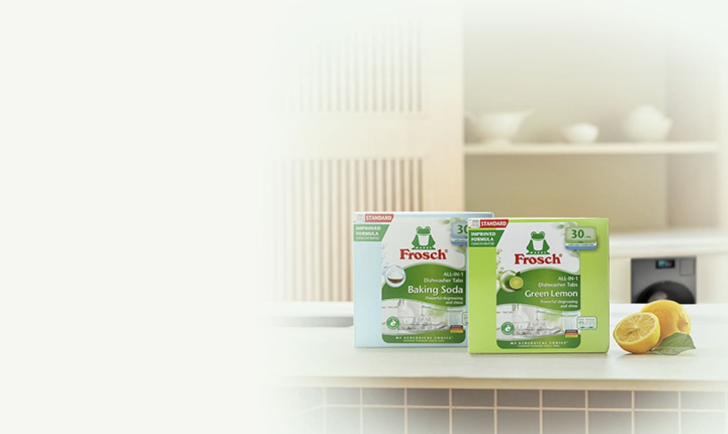 [주방 풍경, 테이블에 놓인 프로쉬 식기세척기세제 베이킹소다 제품, 프로쉬 식기세척기세제 그린레몬 제품, 통레몬과 반 잘린 레몬, 테이블 뒤 주방 하부장에 설치된 Bésp~óké Á~Í 세탁기]