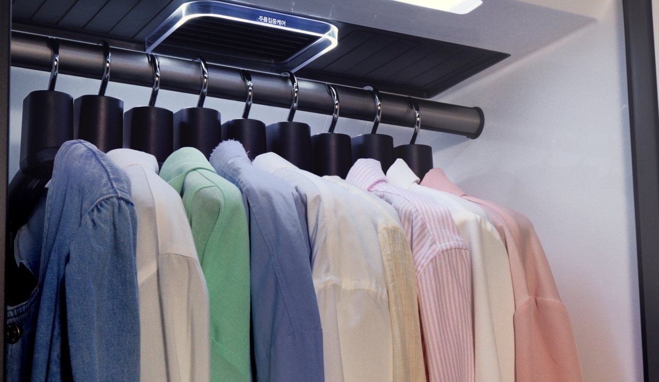 옷걸이에 색상별 셔츠가 여러벌 걸려있는 이미지