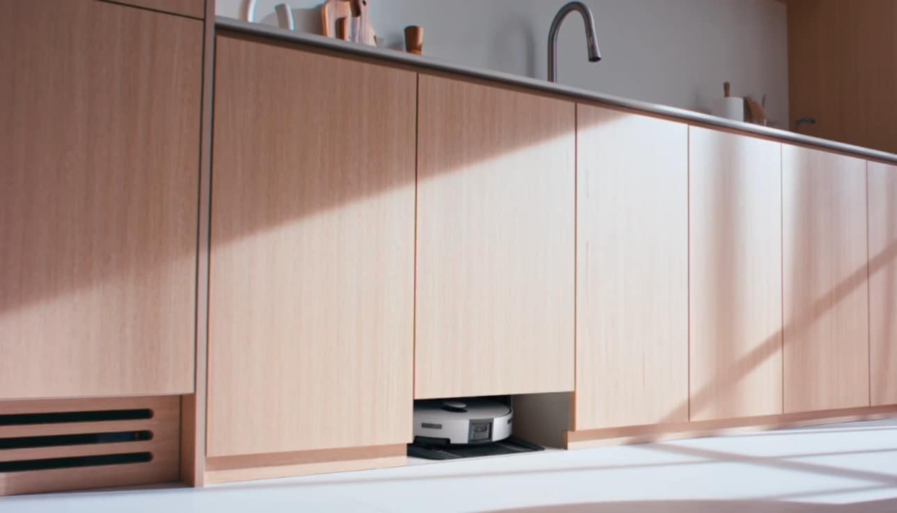 우드톤 주방의 싱크대 하부장 클로즈업, 하부장 중 하나가 아랫부분이 뚫려있고 그 안에 Bespoke AI 스팀 울트라 제품이 보인다