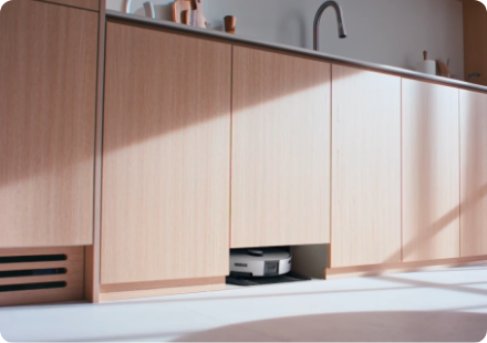 우드톤 주방의 싱크대 하부장 클로즈업, 하부장 중 하나가 아랫부분이 뚫려있고 그 안에 Bespoke AI 스팀 울트라 제품이 보인다