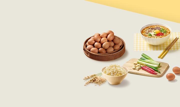 테이블 위의 계란이 쌓여있는 바구니, 노란색 체크 테이블 보 위의 라면 그릇과 나무 젓가락, 발아현미밥, 도마 위의 대파와 고추, 마늘, 그리고 그 옆에 놓인 계란 두 알