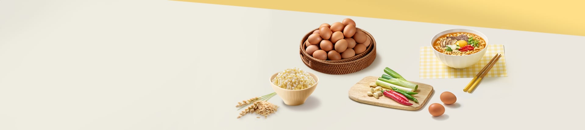 테이블 위의 계란이 쌓여있는 바구니, 노란색 체크 테이블 보 위의 라면 그릇과 나무 젓가락, 발아현미밥, 도마 위의 대파와 고추, 마늘, 그리고 그 옆에 놓인 계란 두 알